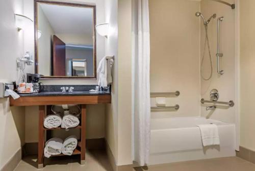 a bathroom with a sink and a tub and a mirror at Comfort Suites Cincinnati Airport in Hebron