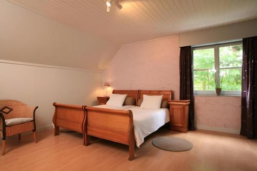 een slaapkamer met een bed, een stoel en een raam bij Pivoné Assebroek in Brugge