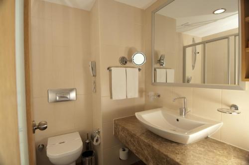 W łazience znajduje się umywalka, toaleta i lustro. w obiekcie Trendy Palm Beach Adult Only w Side