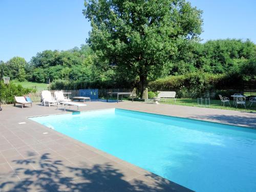 a blue swimming pool with chairs and a tree at Holiday Home Casa dei Ciliegi by Interhome in Moncalieri