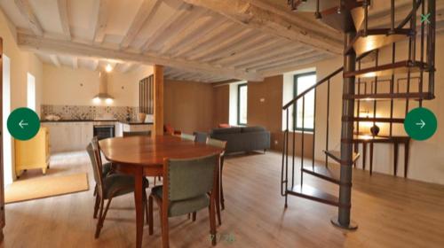 un salon avec une table et des chaises et une cuisine dans l'établissement La demeure de Paule, à Neuvy-au-Houlme