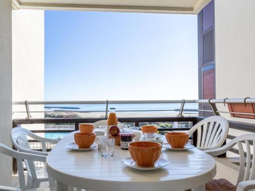 a white table with cups and chairs on a balcony at Apartment Le Sunset-Cap Sud-12 by Interhome in Cap d'Agde