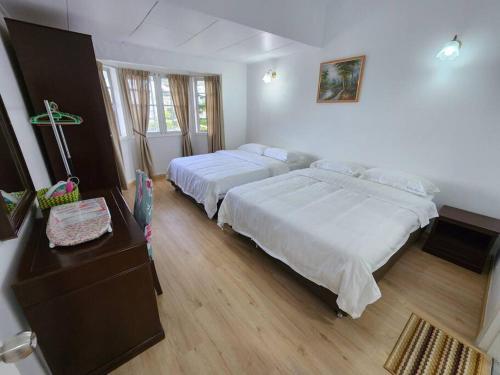 1 dormitorio con 2 camas y una mesa con tocador en Little England B3, en Bukit Fraser
