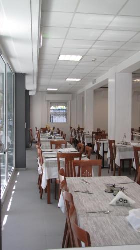una sala da pranzo con tavoli bianchi e sedie in legno di Hotel Vienna a Gabicce Mare