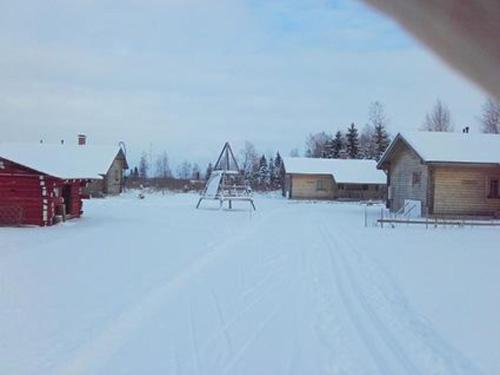 ein schneebedecktes Feld mit Häusern und einem Spielplatz in der Unterkunft Holiday Home Uisku by Interhome in Punkalaidun