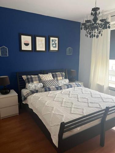 1 dormitorio con 1 cama grande y pared azul en Klimatyzacja - przy centrum Onkologii klinice Novum dla pary bądź 4 osób, en Varsovia