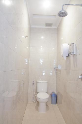 La salle de bains blanche est pourvue d'une douche et de toilettes. dans l'établissement De'Govin Apartment Lombok, à Tjakranegara