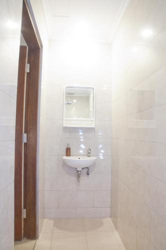 La salle de bains blanche est pourvue d'un lavabo et d'une fenêtre. dans l'établissement De'Govin Apartment Lombok, à Tjakranegara