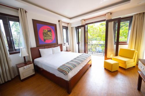 1 dormitorio con 1 cama, 1 silla y ventanas en Fuse Old Town Hoi An, en Hoi An