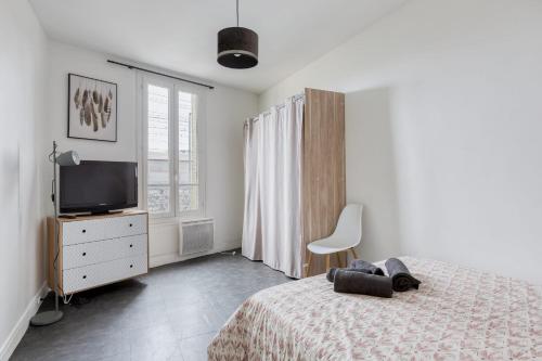 1 dormitorio con 1 cama, TV y silla en Le Lilas Appart Hôtel Near Paris, en Vitry-sur-Seine