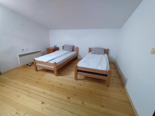 two beds in a room with wooden floors at Ivan Apartment Skopje in Skopje