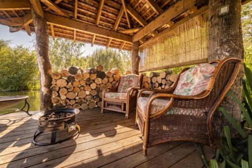 a porch with two chairs and a table and logs at Silver Dollar in Watton