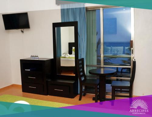 a room with a bedroom with a table and a mirror at Hotel Arrecifes Costamaya in Mahahual