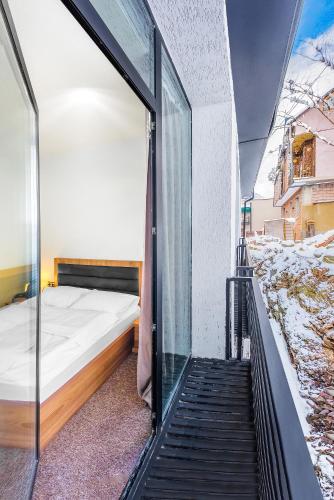 a bedroom with a window and a bed on a balcony at LALO Hotel Abastumani in Abastumani