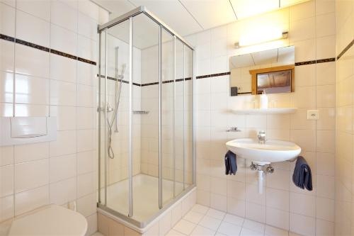 uma casa de banho com um chuveiro e um lavatório. em Hotel Bahnhof em Zermatt