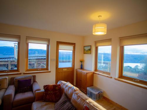 sala de estar con sofá y algunas ventanas en Holiday Home Peter's Shed by Interhome en Drumnadrochit