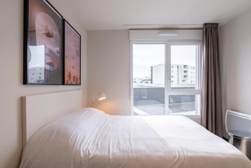 - une chambre avec un lit blanc et une fenêtre dans l'établissement Student Factory Le Havre Les Docks, au Havre