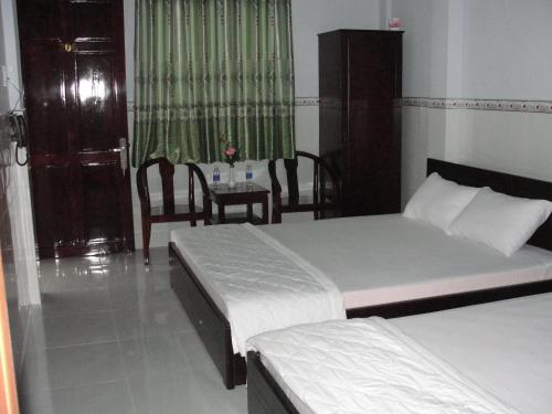 a bedroom with two beds and a table with a chair at Khoa Phu Hotel in Can Tho