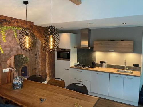 a kitchen with a wooden table and a counter top at Gezellige, luxe bungalow 't pareltje in het bos in Hardenberg "Rheezerveen"woning 20 in Rheezerveen