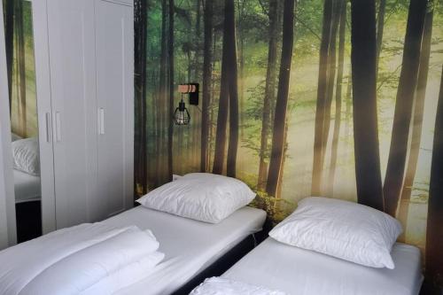 - 2 lits dans une chambre ornée d'une fresque murale représentant des arbres dans l'établissement Gezellige, luxe bungalow 't pareltje in het bos in Hardenberg "Rheezerveen"woning 20, à Rheezerveen