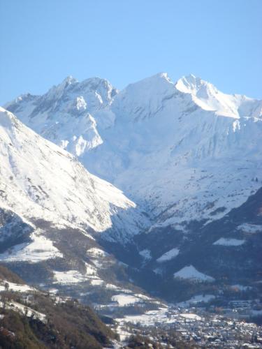a snow covered mountain with a town in front of it at Logis Hôtel Les Cimes in Argelès-Gazost