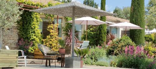 a patio with an umbrella and a table and chairs at Villa Cabrida in Cabrières-dʼAvignon