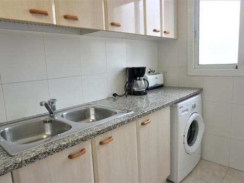 a kitchen with a sink and a washing machine at Villa Service - Rovior 3º 4ª in Calafell