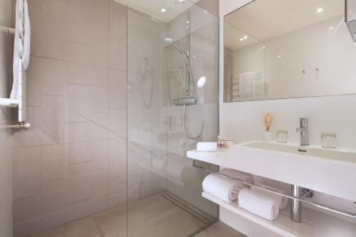 y baño blanco con lavabo y ducha. en Acropole en París