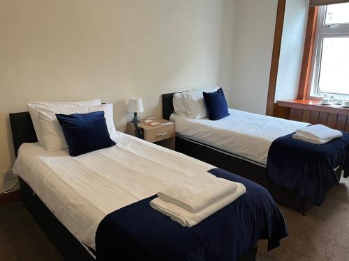 a bedroom with two beds with blue and white sheets at Caithness Inn in Wick