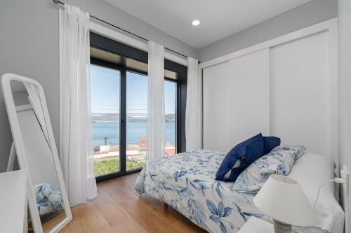 een slaapkamer met een bed en een groot raam bij Casa nueva con piscina y vistas al mar in Vilaboa