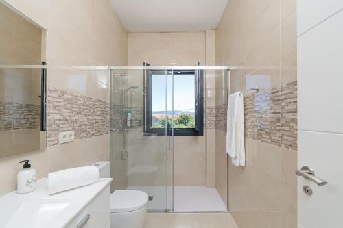 a bathroom with a shower and a toilet and a sink at Casa nueva con piscina y vistas al mar in Vilaboa