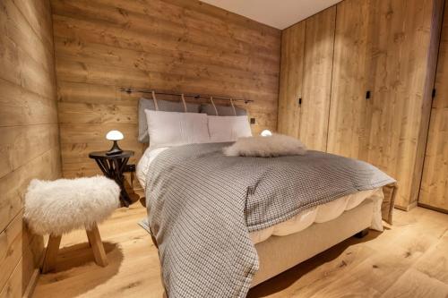 1 dormitorio con 1 cama y pared de madera en Superbe appartement dans luxueux chalet Mt Charvin, en Crest-Voland