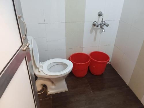 a bathroom with a toilet and two buckets at Sayeban Hotel in Matheran