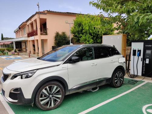 a white car is being charged at a gas pump at Hotel Sausa in Vilafreser