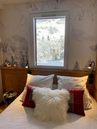 - un lit avec deux oreillers et une fenêtre avec de la neige dans l'établissement T2 de charme à Megeve vue panoramique, à Megève