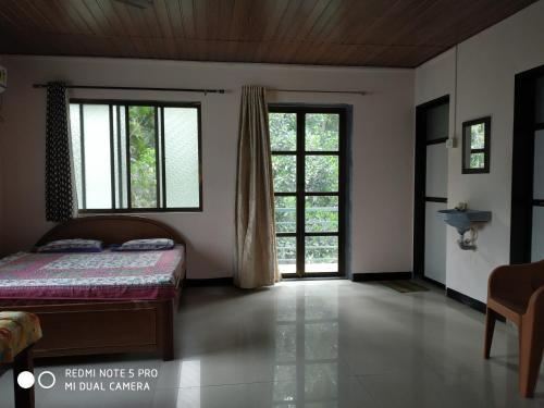 a bedroom with a bed and two windows at Suvarna Holiday Home in Kashid
