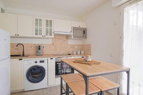 a kitchen with white cabinets and a wooden table at LeRouget : Hypercentre / Jardin aménagé / Hamak in Moissy-Cramayel