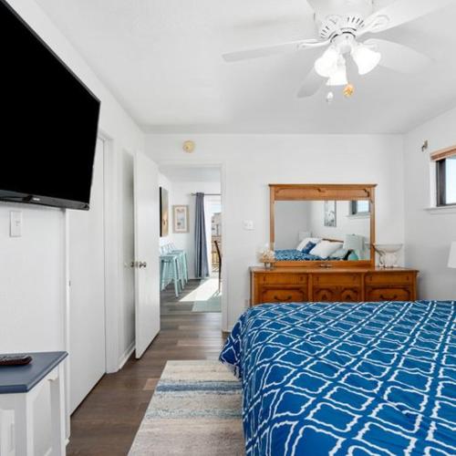 1 dormitorio con 1 cama azul y TV en Walk to the beach Ocean views great yard game room, en Galveston