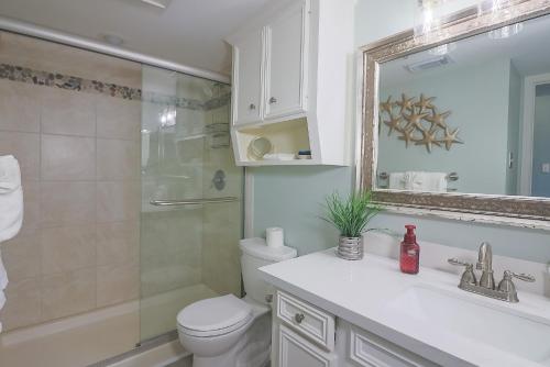 a bathroom with a toilet and a sink and a shower at Charming Beachside Condo Lovely Pool Hot Tubs and Boardwalk in Galveston