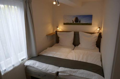 ein kleines Schlafzimmer mit 2 Betten und einem Fenster in der Unterkunft Alte Bäckerei Hamswehrum in Krummhörn