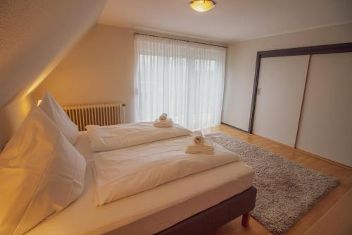 a bedroom with a bed with white sheets and a window at Zur alten Mühle in Krummhörn