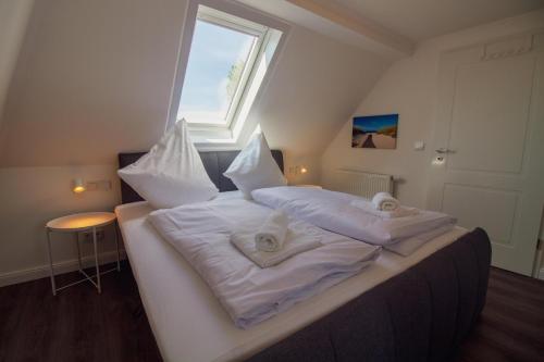 a bedroom with a bed with white sheets and a window at Wolke 7 - Mond in Greetsiel