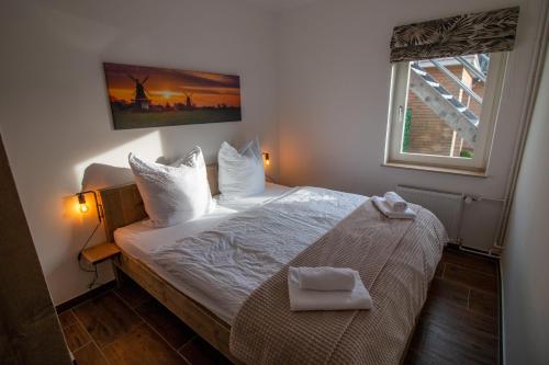 una piccola camera da letto con un letto con lenzuola bianche e una finestra di Das Posthaus - Amt a Greetsiel