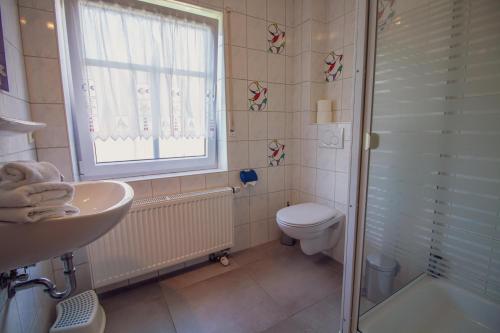 a bathroom with a sink and a toilet and a window at Haus Leuchtturm - Flut in Krummhörn
