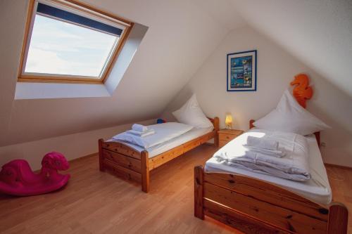 a attic room with two beds and a window at Haus Leuchtturm - Flut in Krummhörn