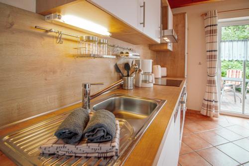 uma cozinha com um lavatório com duas toalhas em Haus Merlin - Silbermöwe em Greetsiel