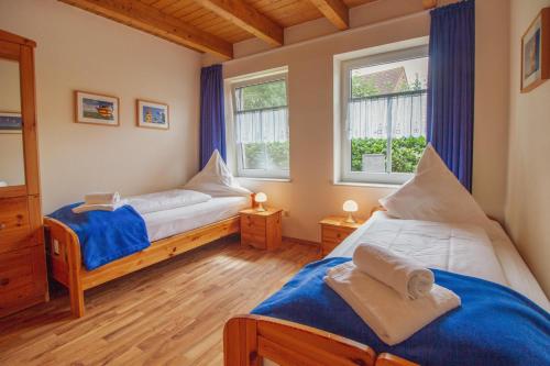 um quarto com 2 camas e 2 janelas em Haus Merlin - Silbermöwe em Greetsiel