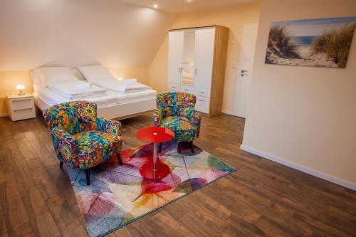 a room with a bed and two chairs and a rug at Huus Viskert in Krummhörn