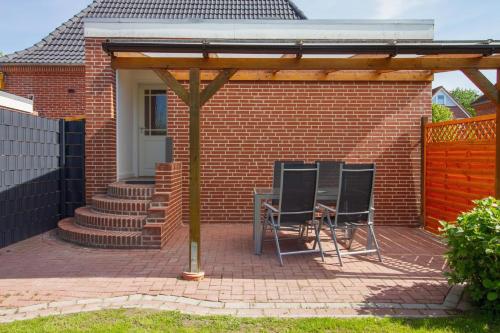 a patio with two chairs and a table in a house at Wolke 7 - Sonne in Greetsiel
