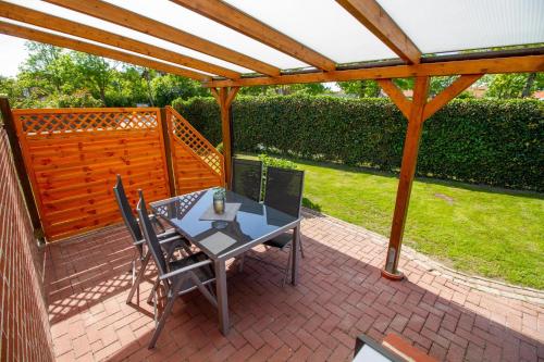 a patio with a table and chairs under a wooden pergola at Wolke 7 - Sonne in Greetsiel